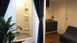 A room with a shower, a sink, and a chair.