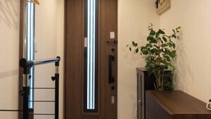 A hallway with a wooden door, a plant, and a metal rack.