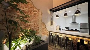 A modern kitchen with a brick accent wall, a bar area with stools, and pendant lighting.