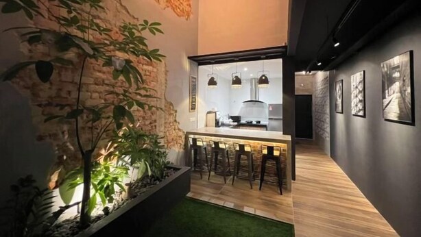 A modern kitchen with a bar area, stone wall, and hanging pendant lights.