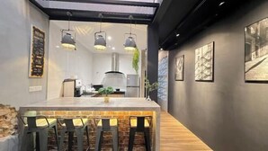 A modern kitchen with a central island, bar stools, pendant lighting, and framed artwork on the walls.