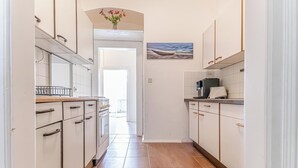 A narrow kitchen with white cabinets, a tiled floor, and a painting on the wall. - Charming 3BR Urban Retreat Vienna (Vienna)