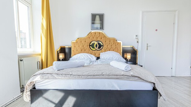 A neatly made bed with a tufted headboard, two bedside lamps, and a framed picture above it. - Charming 3BR Urban Retreat Vienna (Vienna)