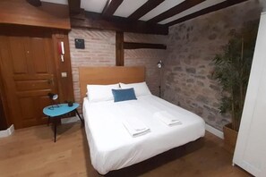 Une chambre à coucher avec un lit, une porte en bois, une petite table et une plante en pot.