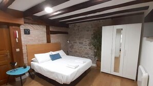 A bedroom with a bed, a small table, a wardrobe, and a clock on the wall. - OLD TOWN NEAR THE BEACH by www.sansebastianapartments.es (San Sebastian)
