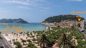 A coastal cityscape with a beach, a hilltop building, and an apartment complex. - OLD TOWN NEAR THE BEACH by www.sansebastianapartments.es (San Sebastian)