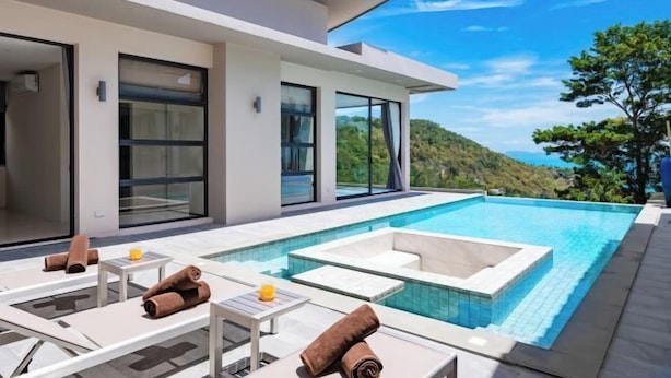 A modern outdoor pool area with lounge chairs and a view of a hillside. - THE PURE BANGPOR (Koh Samui)
