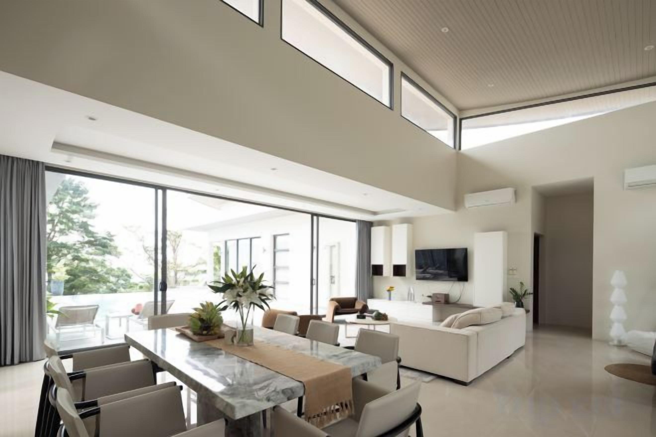 A spacious modern living area with a dining table, seating, and a large window offering a view of the outdoors.