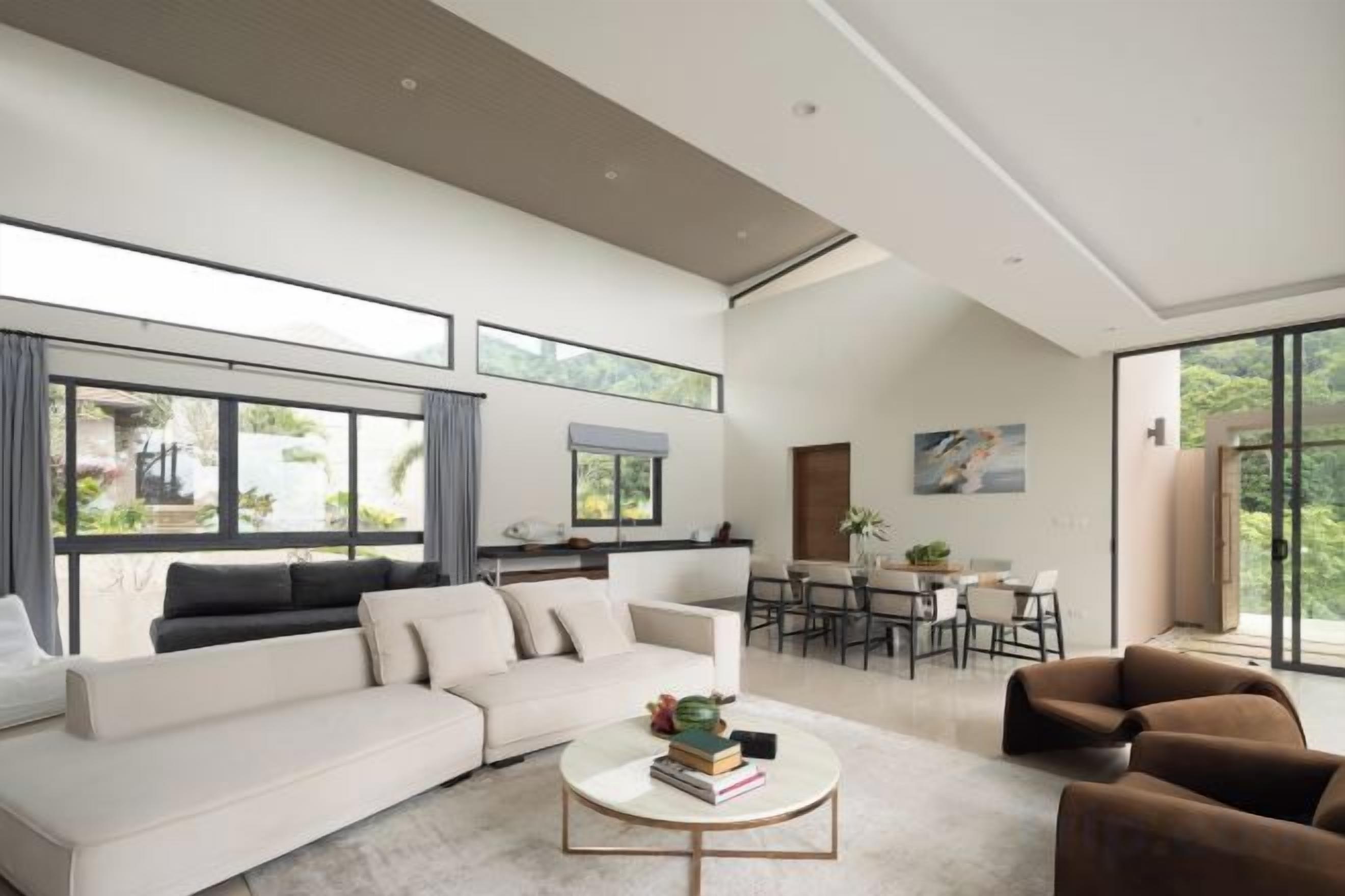 A spacious living area with a large sofa, a coffee table, and a dining area with chairs and a table.