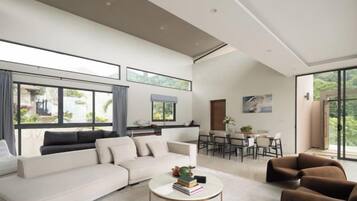 A spacious living area with a large sofa, a coffee table, and a dining area with chairs and a table.