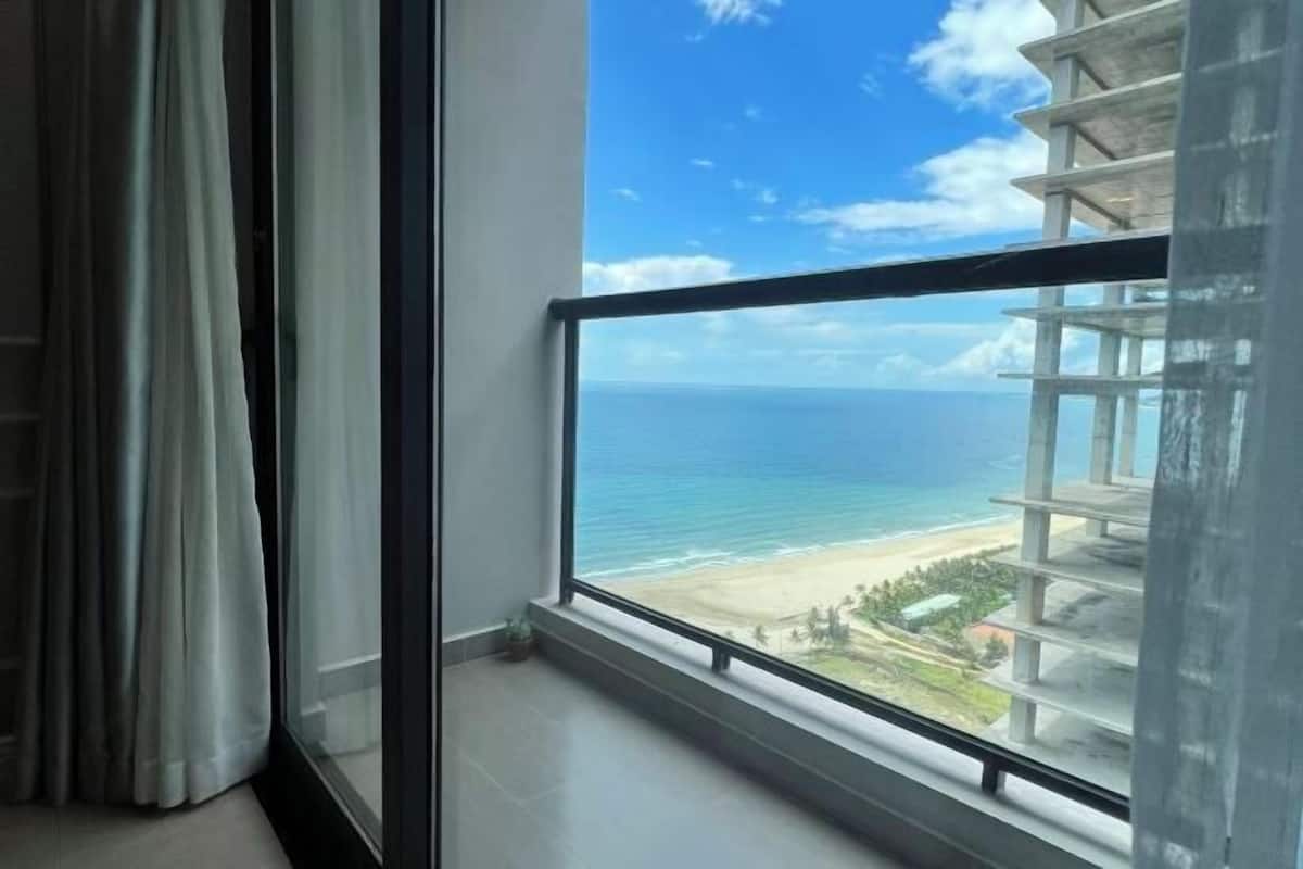 Una stanza con una grande finestra vista spiaggia e un edificio in costruzione.