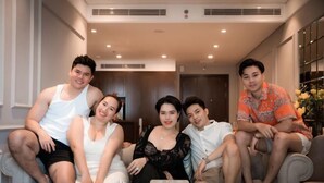 A group of people sitting on a couch in a well-lit room with a modern design, a glass table with a speaker, and a door in the background. - Luxury Ocean View Suites_My Khe Beach_Hinata Apartment (Da Nang)