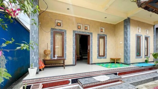 Un edificio tradizionale con facciata in tegole, diverse porte e un piccolo spazio esterno con tavolo e sedie.