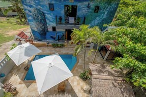 A pool area with umbrellas, a thatched roof, and a mural on the building. - Penthouse Crystal Bay Apartments (Koh Samui)