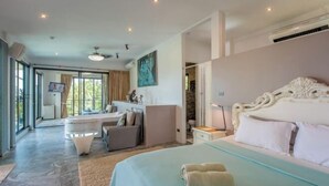 A bedroom with a large bed, a desk, and a chair, with a view of the outdoors. - Penthouse Crystal Bay Apartments (Koh Samui)