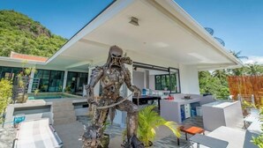 A modern house with a pool, outdoor seating, and a sculpture. - Penthouse Crystal Bay Apartments (Koh Samui)