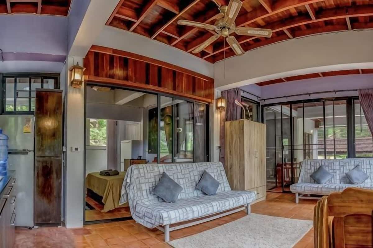 A modern interior with a ceiling fan, a sofa, a dining area, and a kitchen.