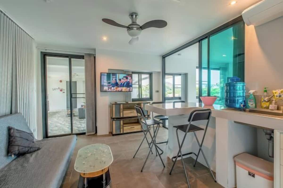 A modern kitchen with a large window, a ceiling fan, and a dining area with chairs.