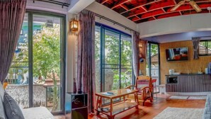 A spacious living area with a sofa, a dining table, and a TV mounted on the wall. - Penthouse Crystal Bay Apartments (Koh Samui)