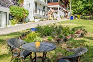 A garden with a table and chairs, a pathway leading to a building, and a statue. - Penthouse Crystal Bay Apartments (Koh Samui)