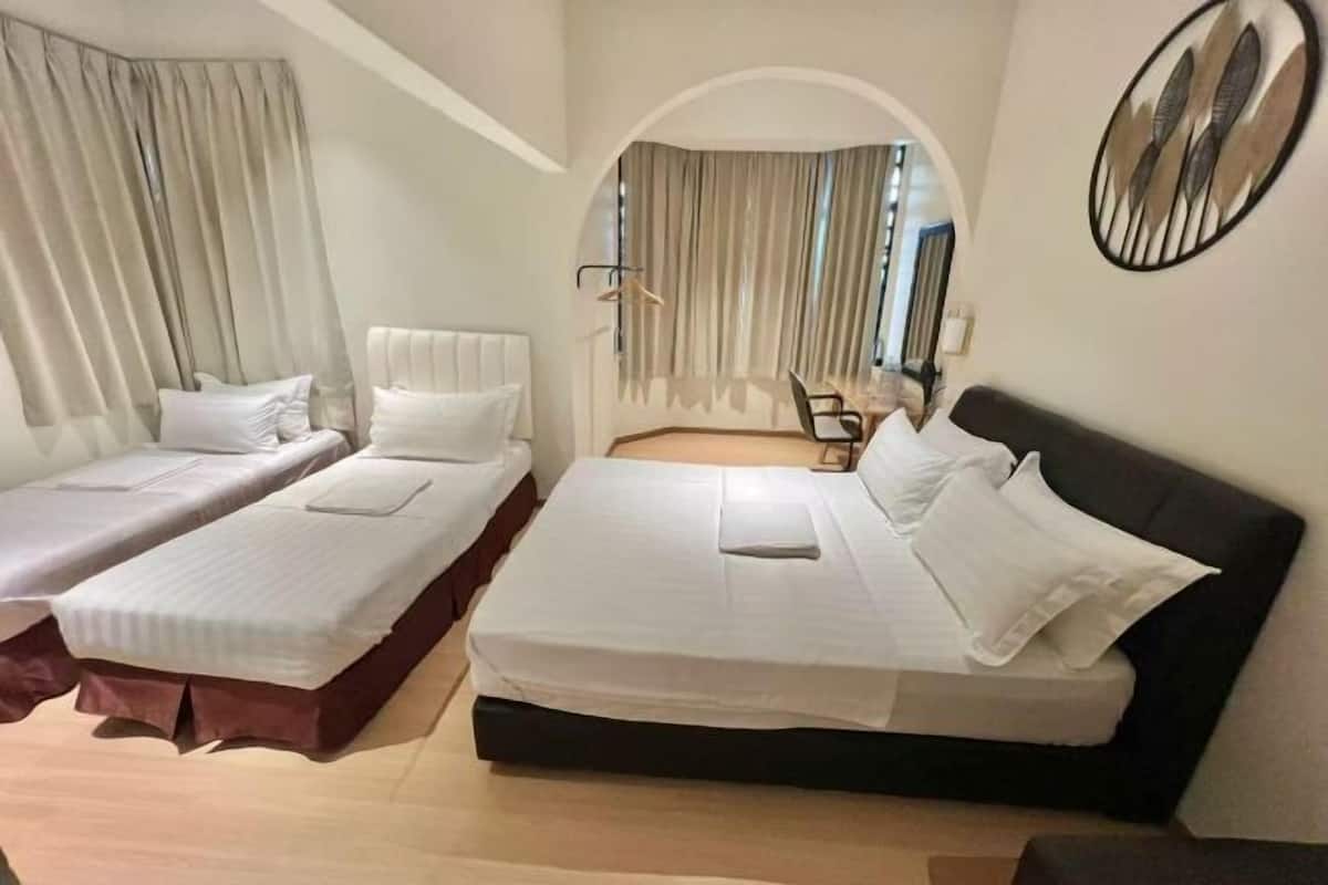 Een hotelkamer met twee eenpersoonsbedden, een groot raam met gordijnen, een ronde spiegel aan de muur en een zithoekje met een stoel en tafel.