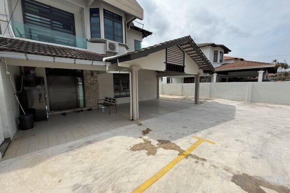 A covered outdoor area with a concrete floor, a yellow line marking, and a building with a tiled roof. - 8 mins driving to T.C Beach @ Holiday Guest House (Kuala Kuantan)
