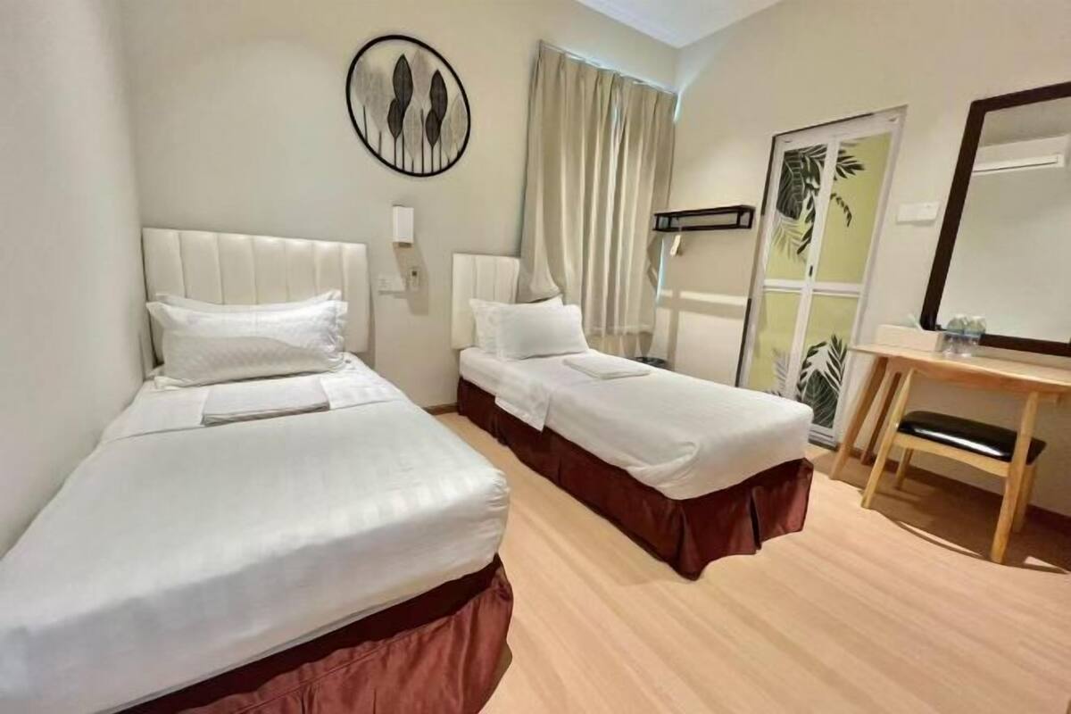 Een hotelkamer met twee bedden, een houten bureau, een spiegel en een kunstwerk aan de muur.