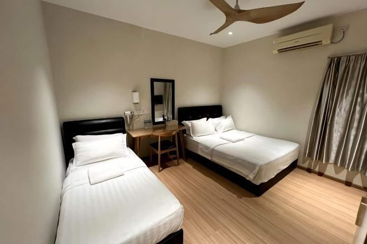 Een hotelkamer met twee bedden, een bureau, een stoel, een plafondventilator en een airconditioning.
