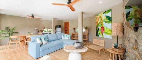 A modern living room with a sectional sofa, a coffee table, and a dining area with a table and chairs.