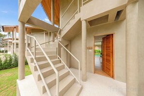 A building with a staircase leading to a covered area, a wooden door, and a sign indicating a room number. - Carbana Lodge, 1 Bedroom - Eco Lodge, Koh Samui (Koh Samui)