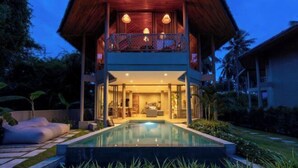 A modern two-story house with a swimming pool, a balcony with a railing, and a well-lit interior. - Carbana Lodge, 1 Bedroom - Eco Lodge, Koh Samui (Koh Samui)