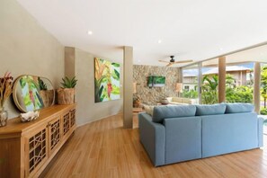 A modern living room with a blue sofa, wooden flooring, and artwork on the walls. - Carbana Lodge, 1 Bedroom - Eco Lodge, Koh Samui (Koh Samui)