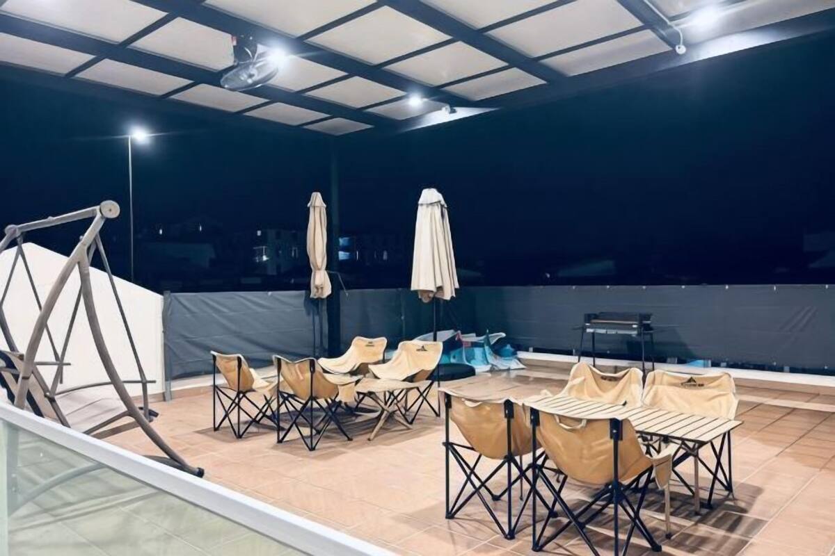 An outdoor patio with a table and chairs, umbrellas, and a swing set.