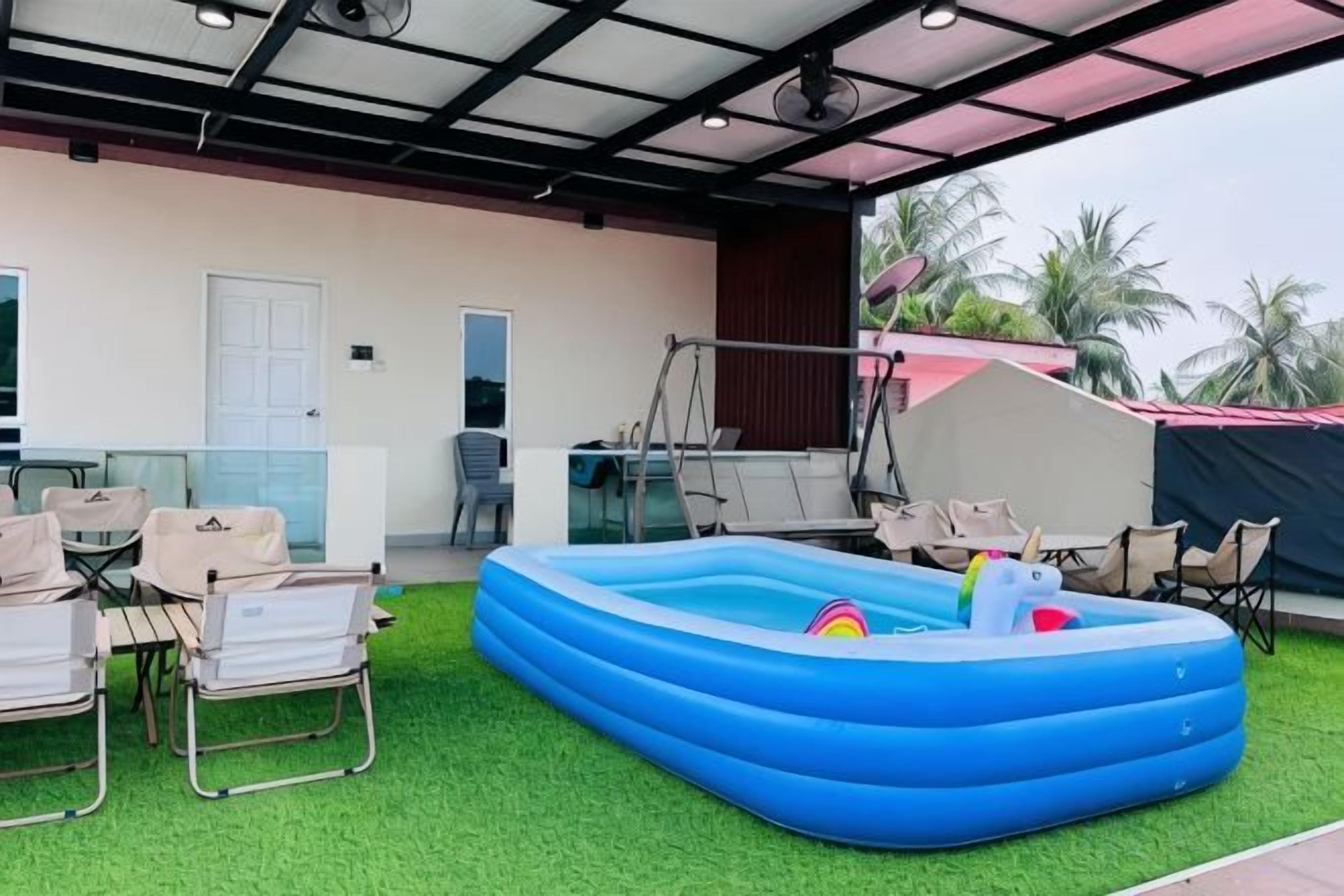Un espace extérieur aménagé avec une piscine gonflable, du gazon synthétique et des coins salon.
