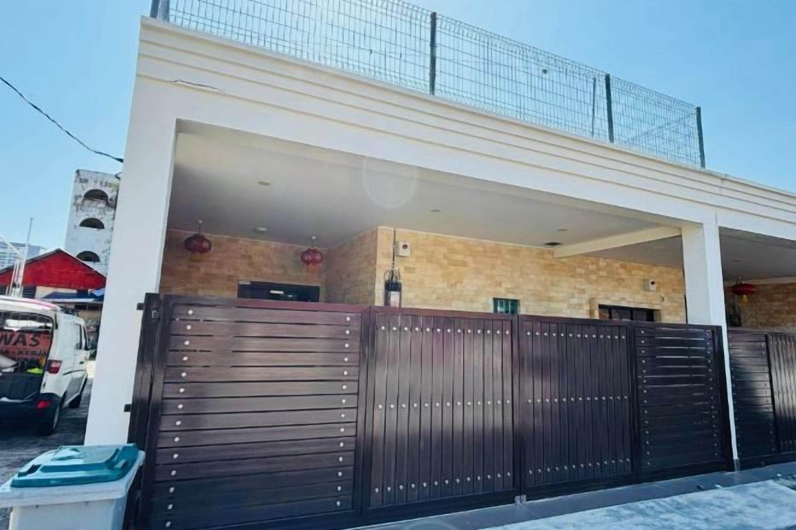 Un bâtiment moderne doté d’une entrée sécurisée par un portail, d’un espace abrité et d’une cheminée bien visible.