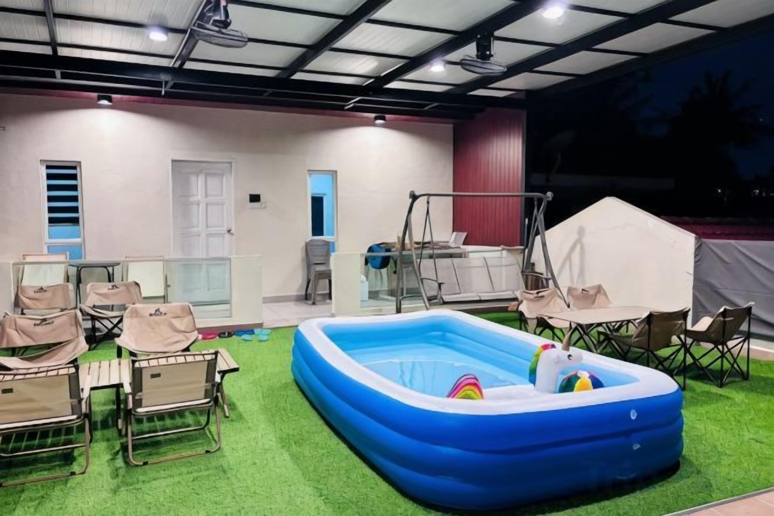 An indoor space with a blue inflatable pool, artificial grass, and seating arrangements.