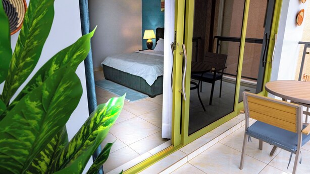 A room with a bed, a chair, a table, and a door leading to an outdoor area.