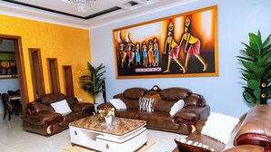 A living room with brown leather sofas, a white coffee table, and a large painting on the wall.