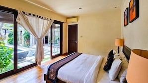 A bedroom with a bed, a window with curtains, a door, and an air conditioning unit. - The Lavana Villa Bukit Jimbaran (2 Bedroom Villa with Private Pool - Minimum Stay 3 Nights) (Bali)