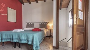 Une chambre à coucher avec un lit, une table de chevet, une lampe et une porte sur laquelle est apposée une pancarte.