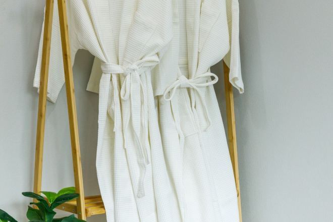 Un peignoir blanc est suspendu à un porte-vêtements en bois.