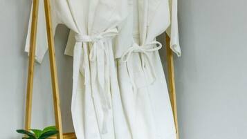 Un peignoir blanc est suspendu à un porte-vêtements en bois.