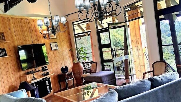 A modern living room with a large sectional sofa, a wooden TV stand, and a dining area with a table and chairs.