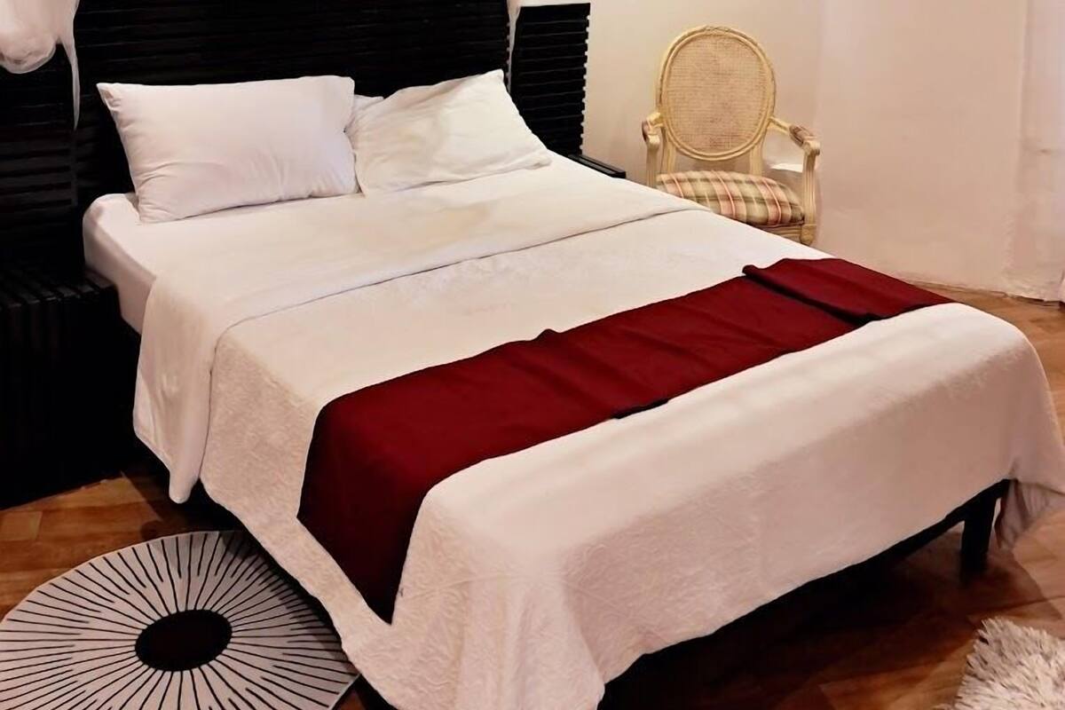 Une chambre bien rangée, avec un lit, des tables de chevet, une chaise et un tapis rond.