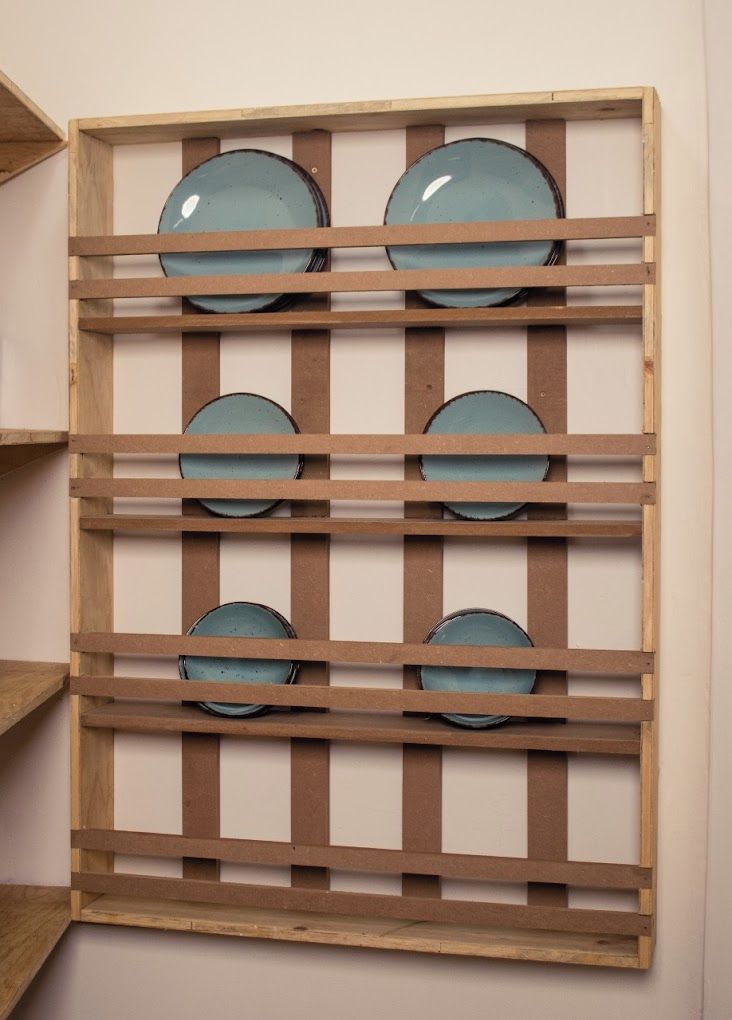 A wooden wall-mounted rack with six circular plates.