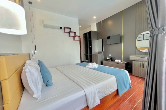 A hotel room with a bed, bedside table, TV, and a mirror.