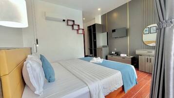 A hotel room with a bed, bedside table, TV, and a mirror.