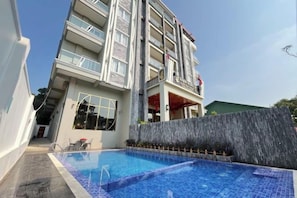 Ein Hotel mit Schwimmbad, ein mehrstöckiges Gebäude und ein klarer Himmel.