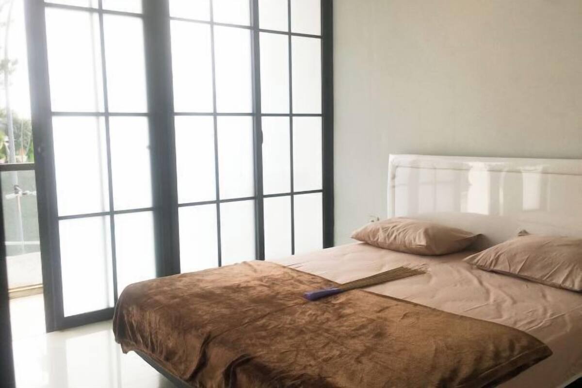 Un dormitorio con cama, almohadas, ventana y puerta.