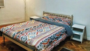 A bedroom with a patterned bedspread, a nightstand, and a bedside table. - Jessy Residential Apartment (Cairo)
